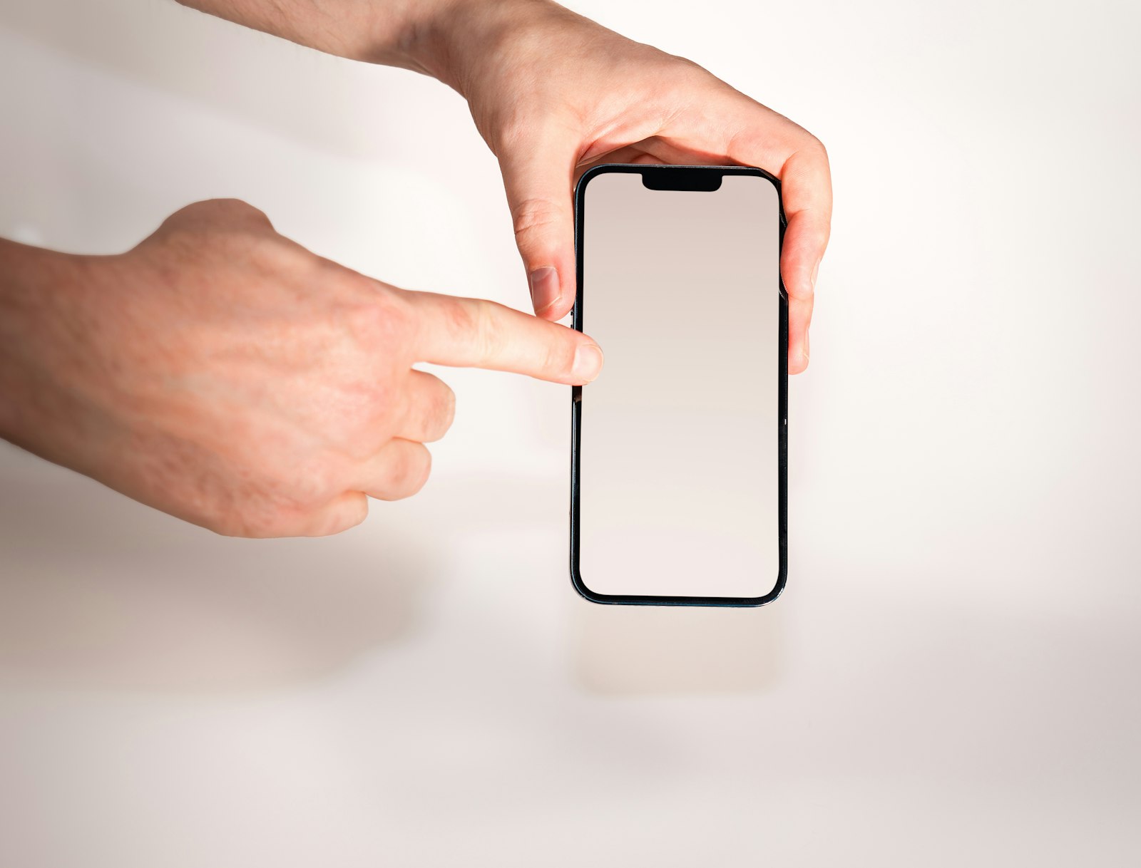片手でスマートフォンを持ち、もう片方の手の人差し指で画面に触れようとしている手元
