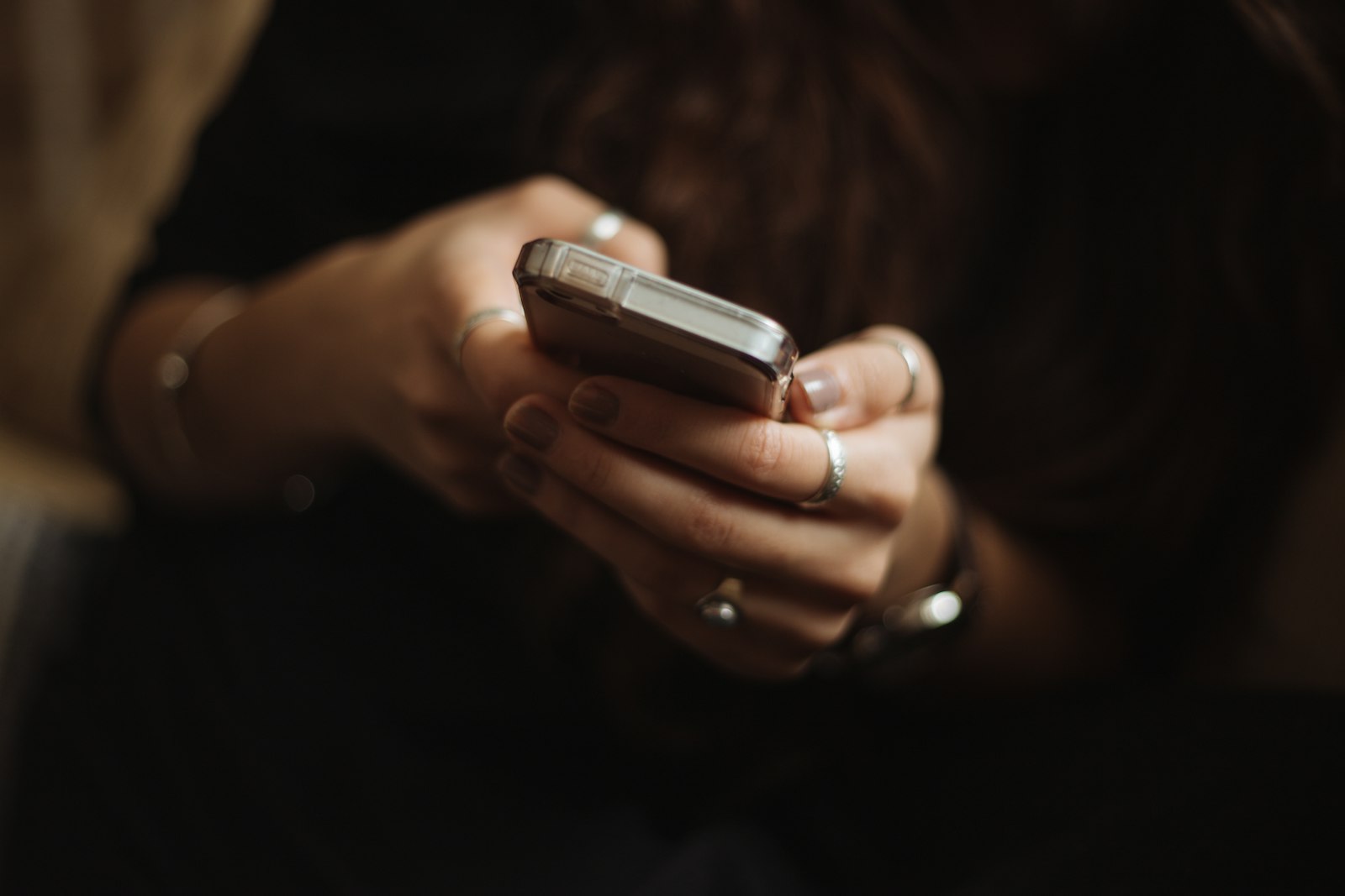 指輪をした両手でスマートフォンを持ち、親指で文字を入力している手元
